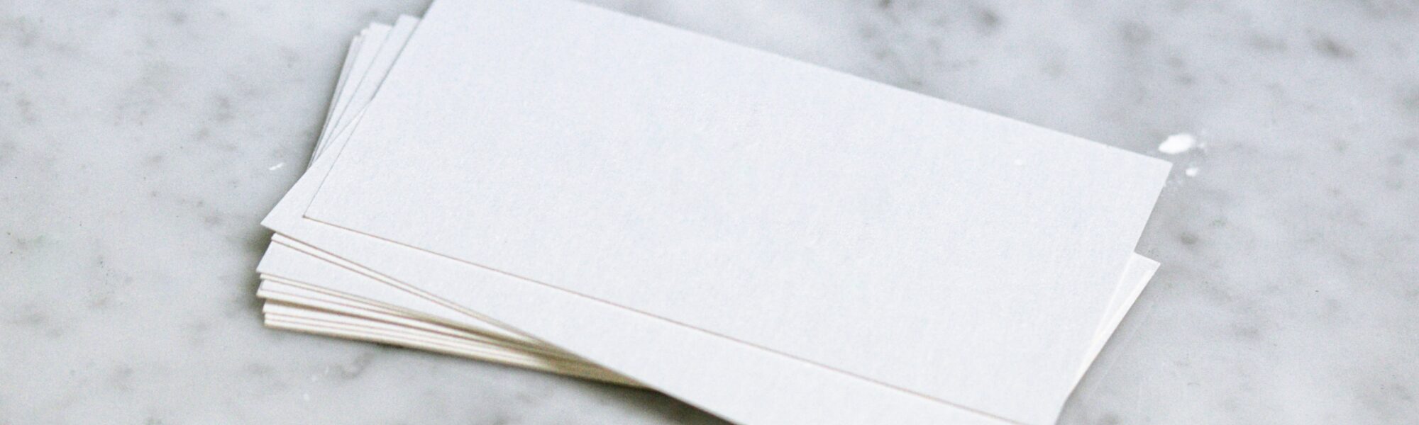 Ein Stapel weißes Papier liegt auf einer Marmorplatte.