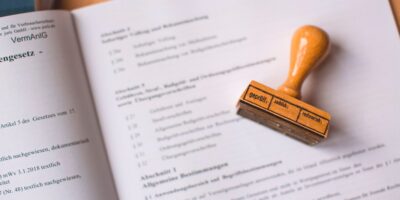 Ein Stempel aus Holz liegt auf einem aufgeschlagenem Buch.